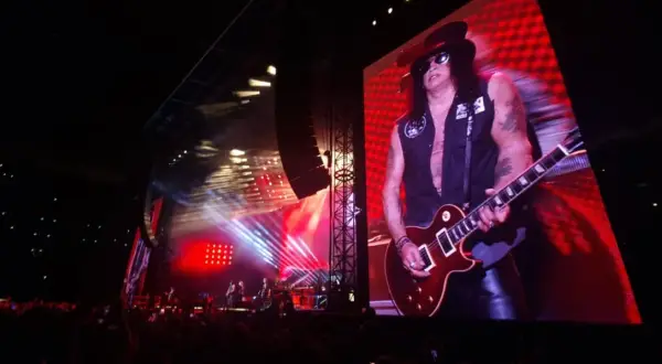 Slash z Guns N' Roses gra na gitarze na wielkim ekranie podczas koncertu w Warszawie.