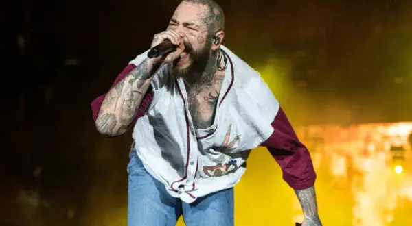 Post Malone śpiewa na koncercie w koszulce z Królikiem Bugsem i dżinsowych szortach.
