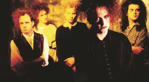 Zespół The Cure w charakterystycznych fryzurach i makijażu. Ich mroczne utwory niosą emocje.
