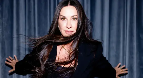 Alanis Morissette z rozwianymi włosami, w czarnej marynarce, gotowa na koncert.