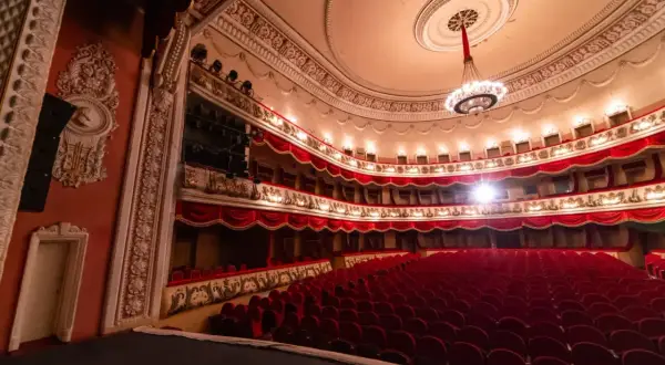 Wnętrze teatru z czerwonymi fotelami i lożami, gotowe na wspaniałe arie operowe.