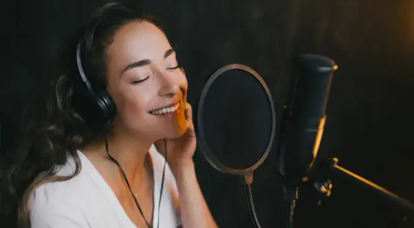 Kobieta w słuchawkach śpiewa do mikrofonu. Czy to magia autotune co to?