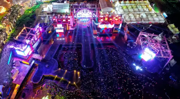 Widok z lotu ptaka na nocny koncert z tłumem i oświetloną sceną.