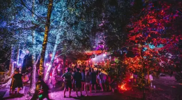 Nocny las rozświetlony kolorowymi światłami, tłum ludzi bawi się na Garbicz Festival.