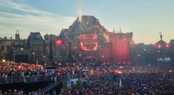 Tłum ludzi na jednym z największych festiwali muzycznych w Europie. Na scenie wulkanicznej wyświetlane jest imię Steve Angello, a nad głowami publiczności latają czerwone konfetti.