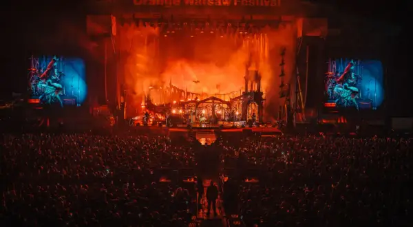 Koncert na Orange Warsaw Festival. Tłum ludzi pod sceną, na której trwa widowiskowe show z efektami pirotechnicznymi.