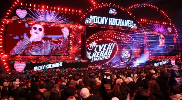 Koncert WOŚP 2026: tłumy ludzi pod sceną, na ekranach artyści, czerwone światła i serca WOŚP.