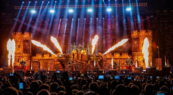 Koncert Sabaton z pirotechniką i scenografią zamku, widziany z perspektywy publiczności.