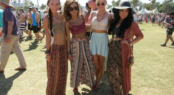 Cztery młode kobiety w letnich strojach pozują na tle festiwalu Coachella.