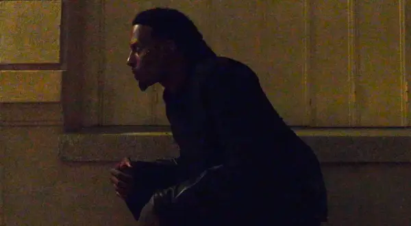 Playboi Carti w Polsce, siedzi w mroku, czekając na coś.
