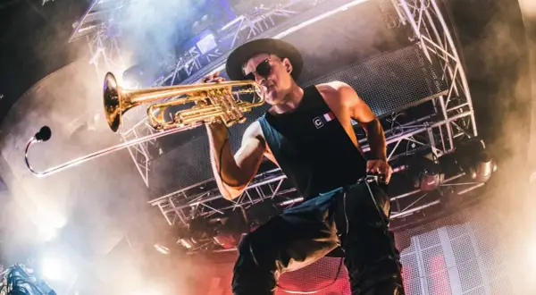 Timmy Trumpet gra na trąbce na scenie podczas koncertu.