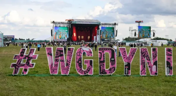 Różowe litery #WGDYNI na trawie przed sceną festiwalową Open'er.