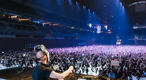 DJ Boris Brejcha w masce gra dla tłumu fanów na koncercie w hali.