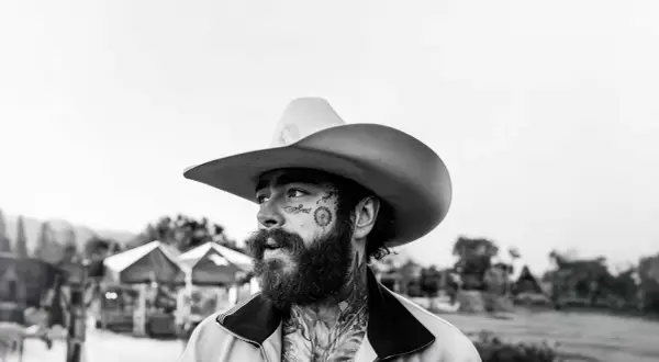 Post Malone w kowbojskim kapeluszu, z tatuażami na twarzy, gotowy na swój kolejny koncert.