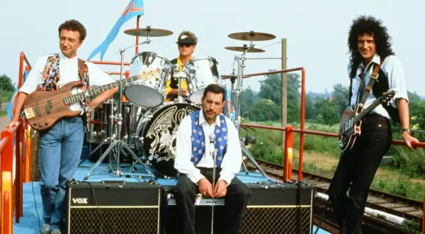 Zespół Queen na wagonie kolejowym, gotowy do niezapomnianych koncertów. Freddie Mercury, Brian May, John Deacon i Roger Taylor.