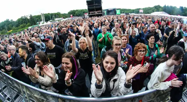 Tłum na koncercie w Poznaniu, fani klaszczą i cieszą się występem. Widoczny fragment sceny i festiwalowej atmosfery.