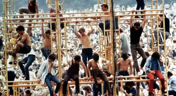 Ludzie wspinający się na żółtą konstrukcję podczas festiwalu Woodstock 1969.