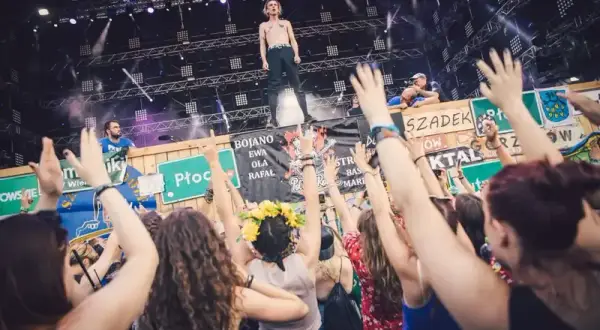 Energiczny tłum na czaplinek festiwal, z rękami w górze, podczas koncertu. Wokalista na scenie, fani szaleją.