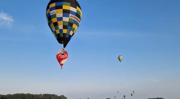 Balony unoszą się na niebie, przypominając o znaczeniu 99 luftballons. W oddali widać więcej balonów.