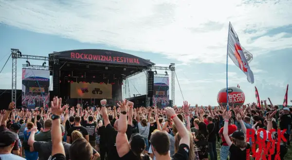 Tłum ludzi z rękami w górze na festiwalu Rockowizna przed sceną.