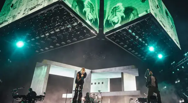 Energetyczny linkin park opener na scenie. Wokalista śpiewa, zespół gra, a nad nimi ogromne ekrany z zielonymi wizualizacjami.