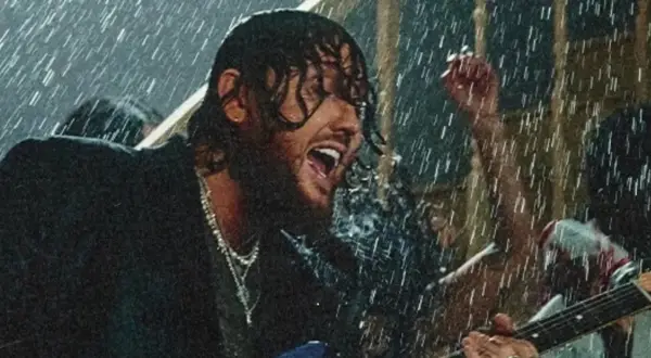 James Arthur śpiewa w deszczu w Warszawie, grając na gitarze.