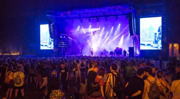 Tłum ludzi na OFF Festivalu, podziwiający koncert na oświetlonej scenie.