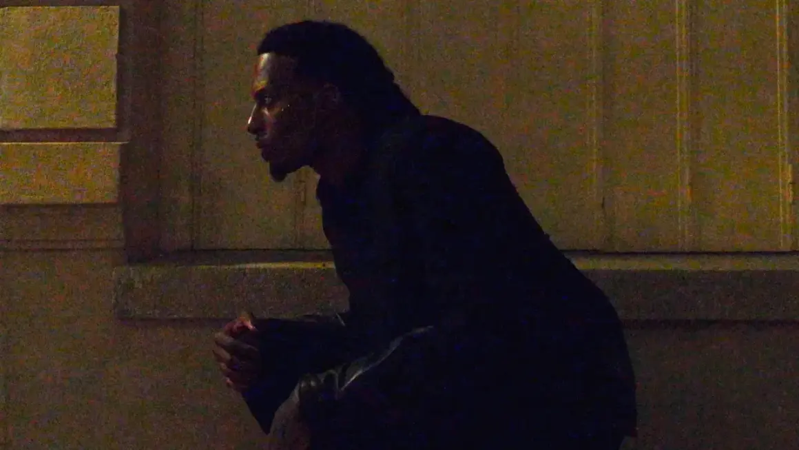 Playboi Carti w Polsce, siedzi w mroku, czekając na coś.