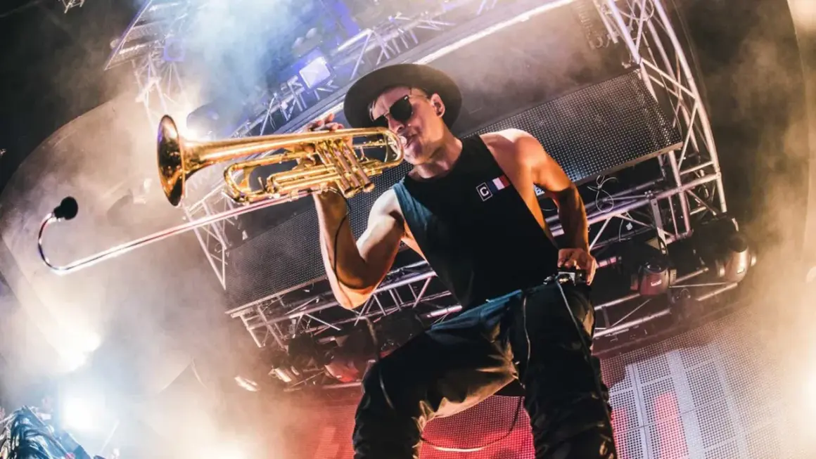 Timmy Trumpet gra na trąbce na scenie podczas koncertu.