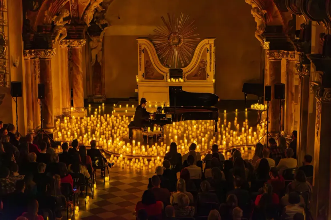 Pianista gra na fortepianie otoczony tysiącami świec, przed publicznością.