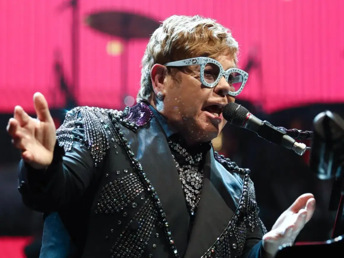 Elton John w błyszczącej marynarce śpiewa na jednym ze swoich niezapomnianych koncertów.