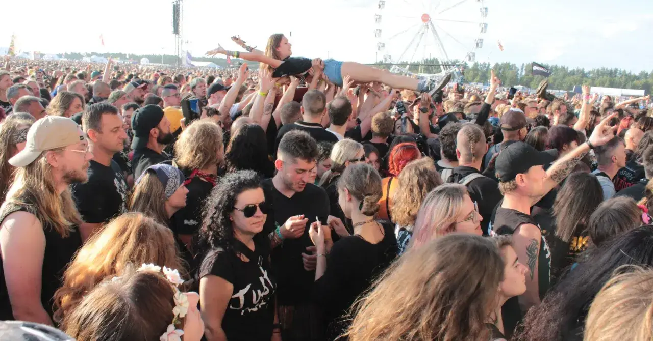 Tłum na czaplinek festiwal unosi kobietę w powietrze. W tle wesołe miasteczko.