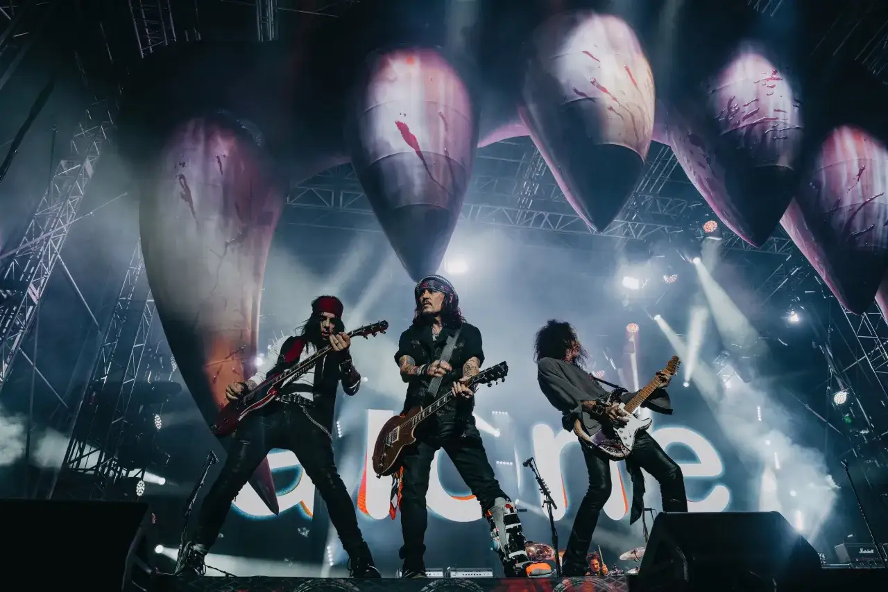 Hollywood Vampires na scenie, grający rockowe kawałki. W tle gigantyczne, krwawe kły.