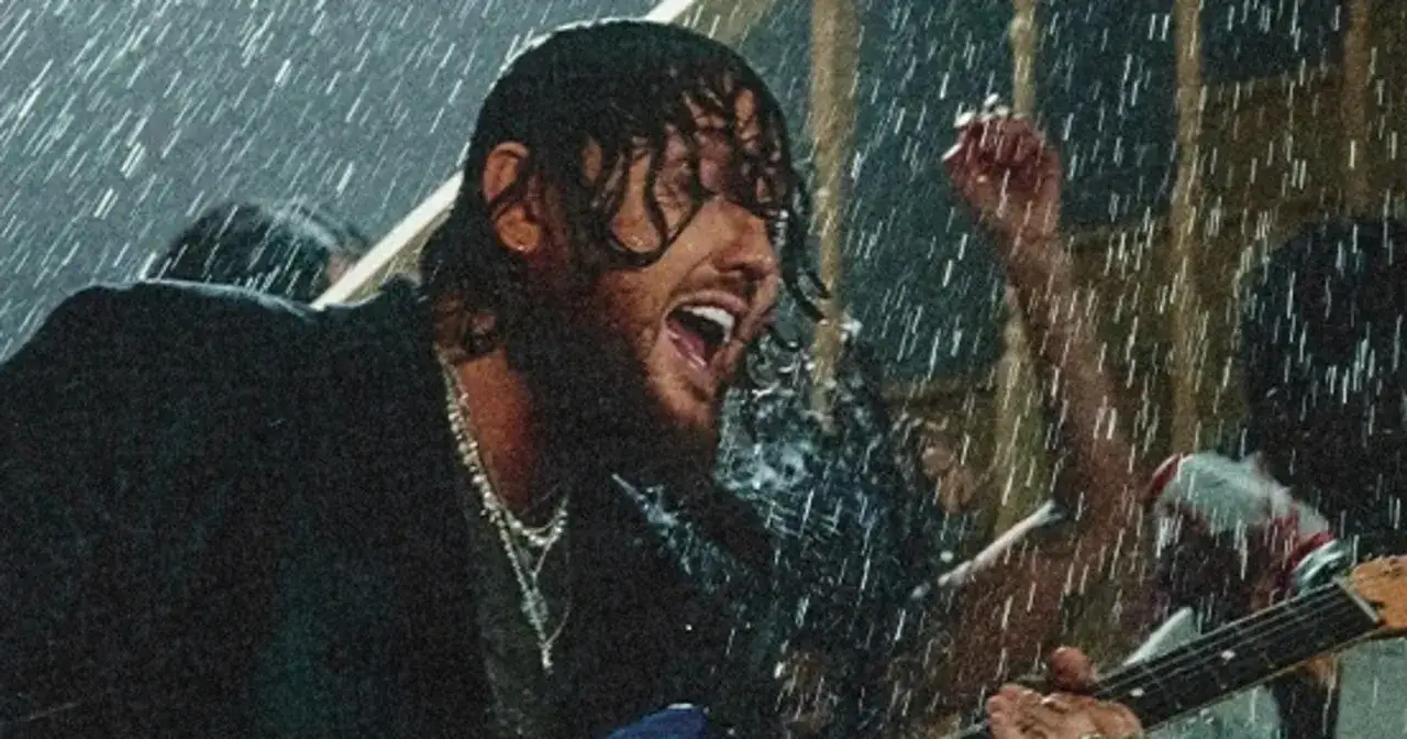 James Arthur śpiewa w deszczu w Warszawie, grając na gitarze.