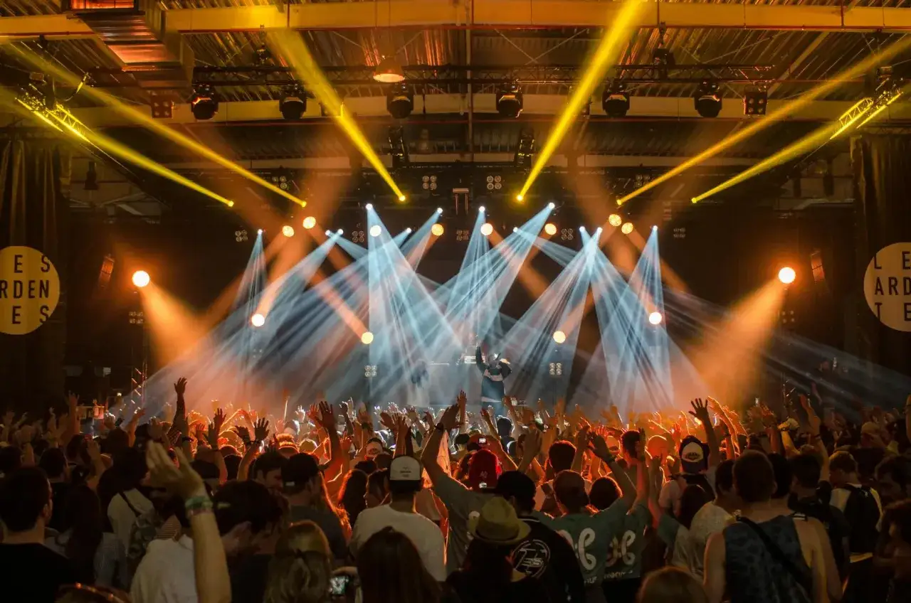 Tłum na koncercie, ręce w górze, światła sceniczne tworzą atmosferę bittersweet festival.