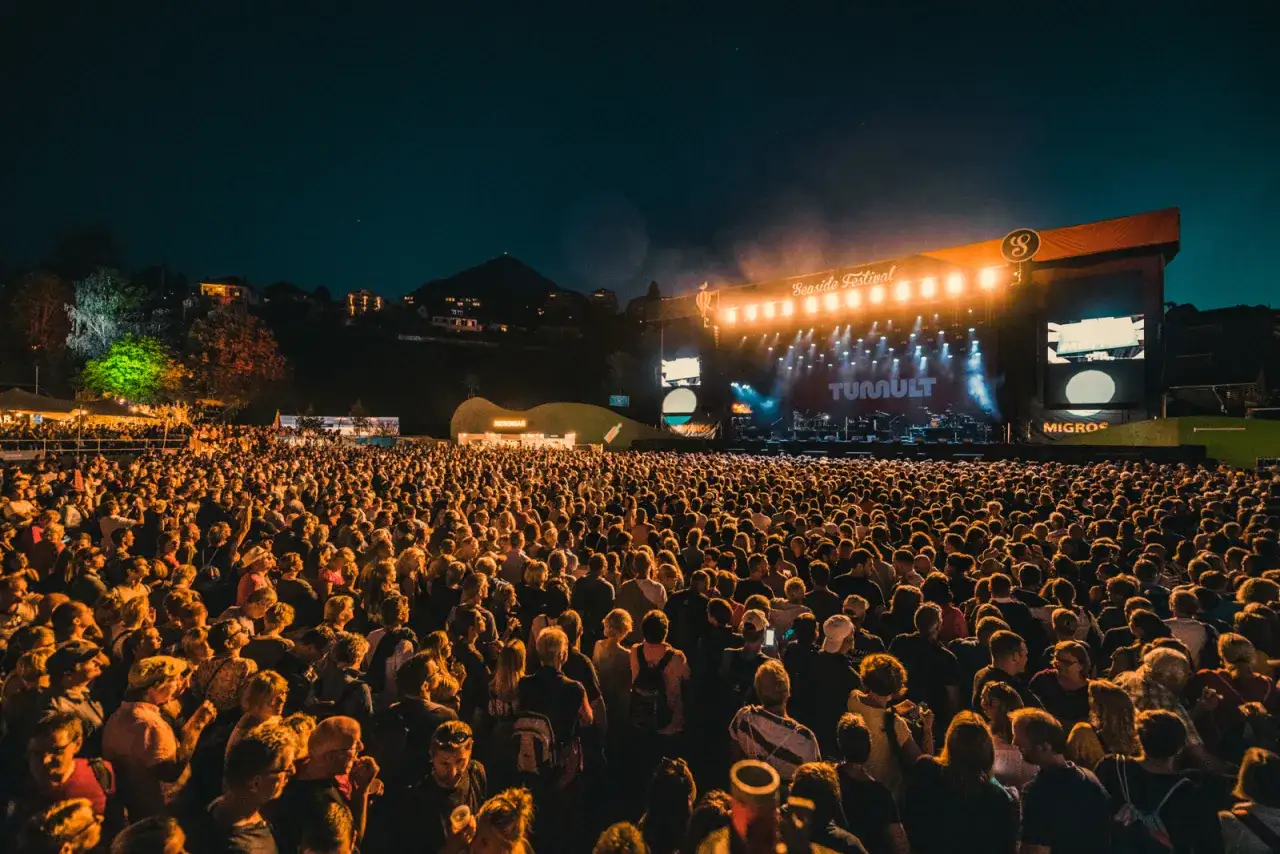 Tłum ludzi na nocnym seaside festival, oświetlony sceną z napisem 