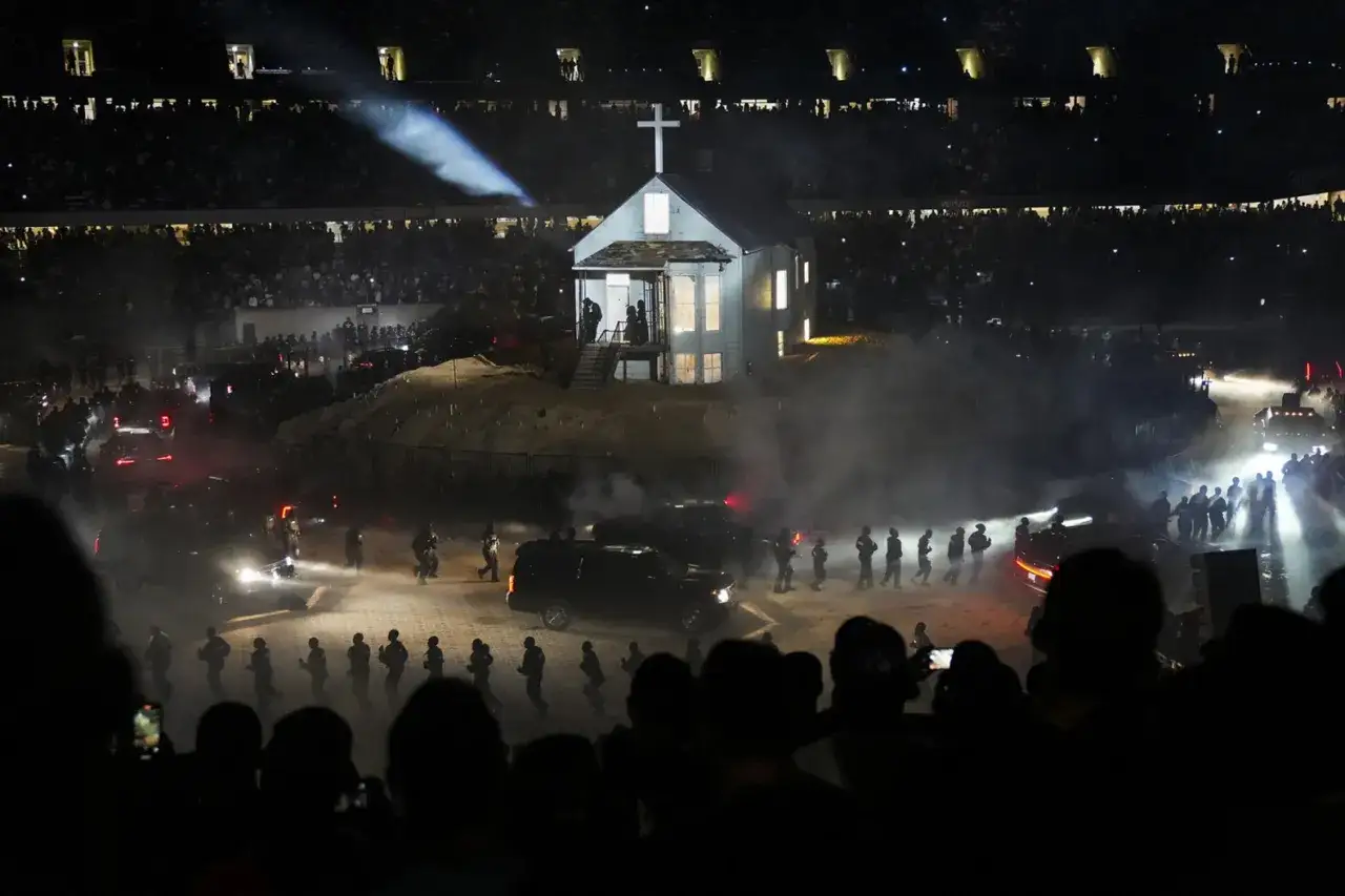 Scena z koncertu Donda 2: biały kościół na wzgórzu, otoczony przez ludzi i samochody, w dymie i świetle reflektorów.