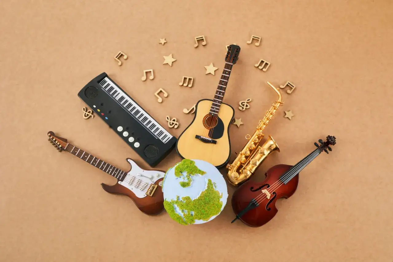 Proste instrumenty muzyczne: keyboard, gitara elektryczna, gitara akustyczna, saksofon, skrzypce, otaczają zieloną kulę ziemską.