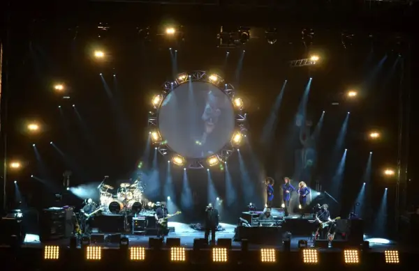 Koncert The Australian Pink Floyd Show z okrągłym ekranem i muzykami na scenie.