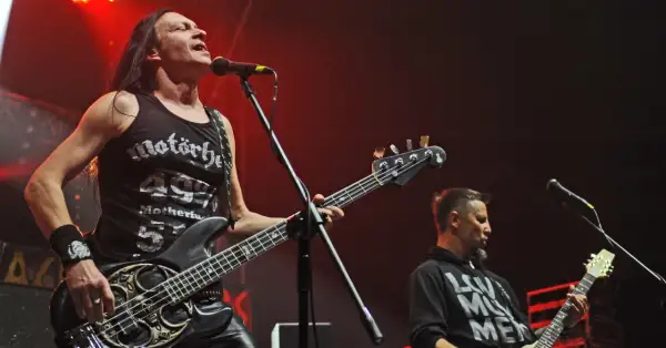 Dwóch muzyków Acid Drinkers grających na gitarach basowych na scenie.