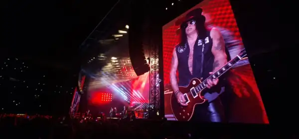 Slash z Guns N' Roses gra na gitarze na wielkim ekranie podczas koncertu w Warszawie.