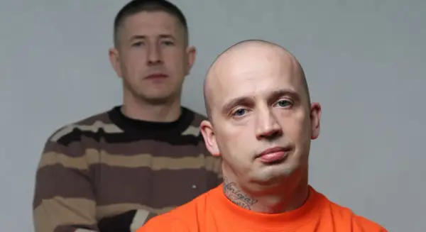 Dwóch mężczyzn, jeden z przodu w pomarańczowej koszulce i tatuażem na szyi, drugi z tyłu w bluzie w paski.