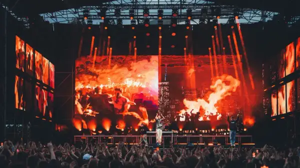 Koncert na festiwalu z ognistą scenografią i tłumem widzów.