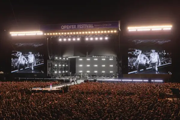 Tłum szaleje na opener festiwal w sobotę. Na scenie artyści, a na telebimach ich wizerunki.