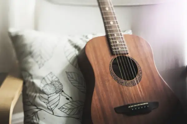 Akustyczna gitara obok poduszki z liśćmi. Idealna do grania harcerskie piosenki chwyty przy ognisku.