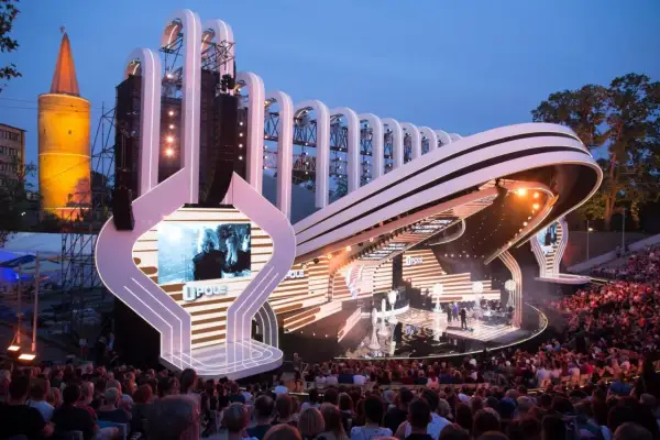 Scena Festiwalu Opole z widownią i charakterystyczną wieżą w tle. Widać elementy programu i artystów.