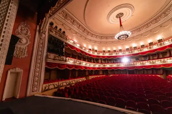 Wnętrze teatru z czerwonymi fotelami i lożami, gotowe na wspaniałe arie operowe.