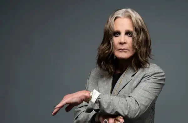 Ozzy Osbourne w szarej marynarce, z charakterystycznym makijażem oczu. Ikona rocka, której ozzy osbourne utwory wciąż inspirują.