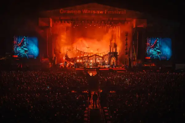 Koncert na Orange Warsaw Festival. Tłum ludzi pod sceną, na której trwa widowiskowe show z efektami pirotechnicznymi.