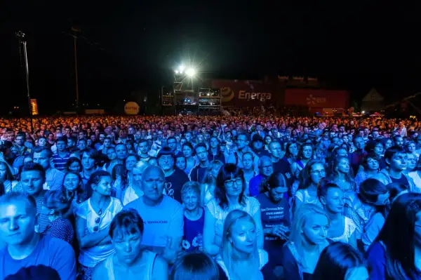 Tłum ludzi na koncercie, oświetlony niebieskim i pomarańczowym światłem. W tle widać banery z logo Energa i Lotos. To prawdziwa inwazja mocy, jak na koncercie Scorpions!